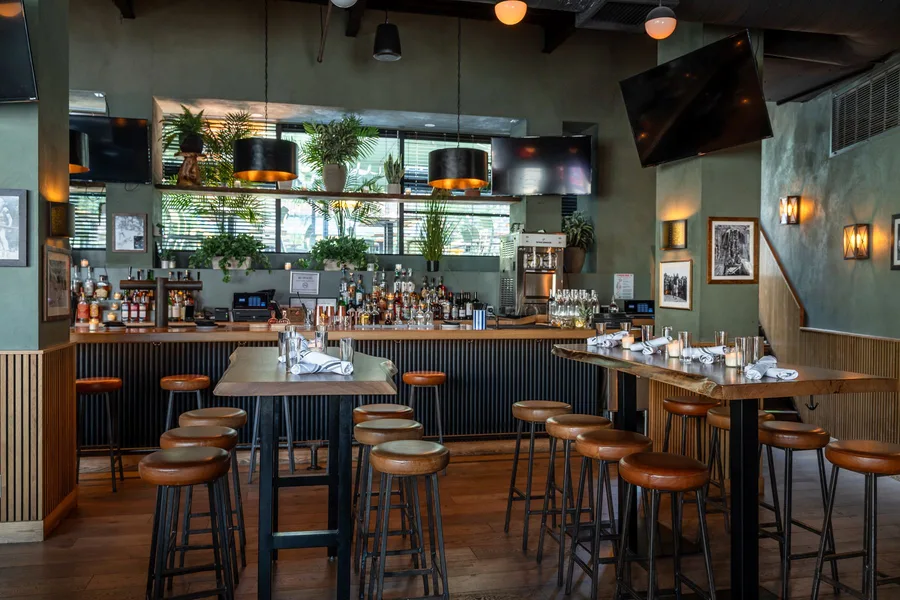 The downstairs bar at The Rutherford, screens tuned in above the taps and bottles