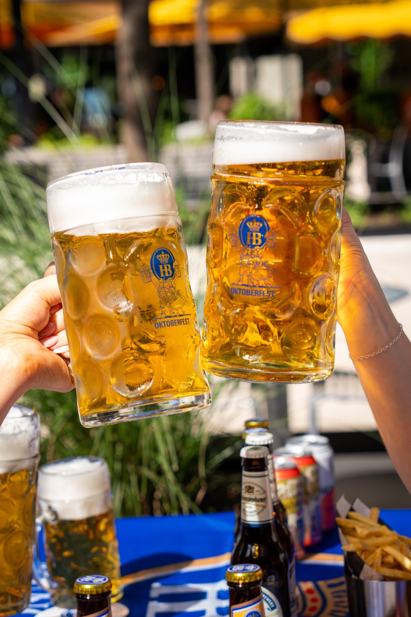 Two guests clinking liter steins of Oktoberfest lager together