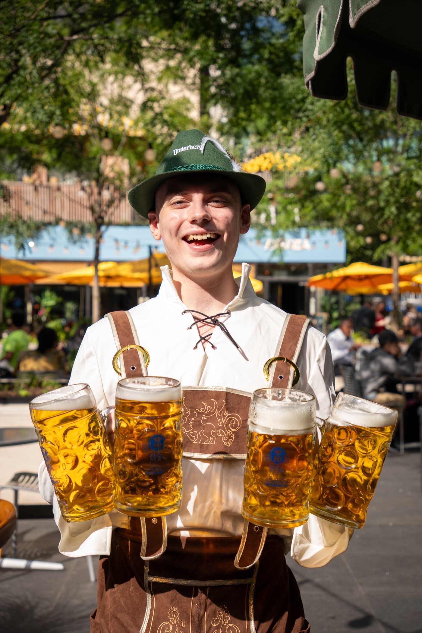 A server in traditional lederhosen carrying four liter steins of Oktoberfest lager on the rooftop