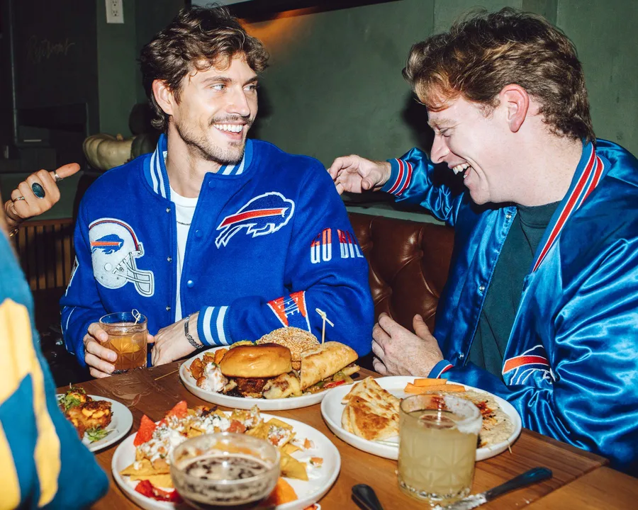 Buffalo Bills fans sharing a table piled with burgers, nachos, and quesadillas