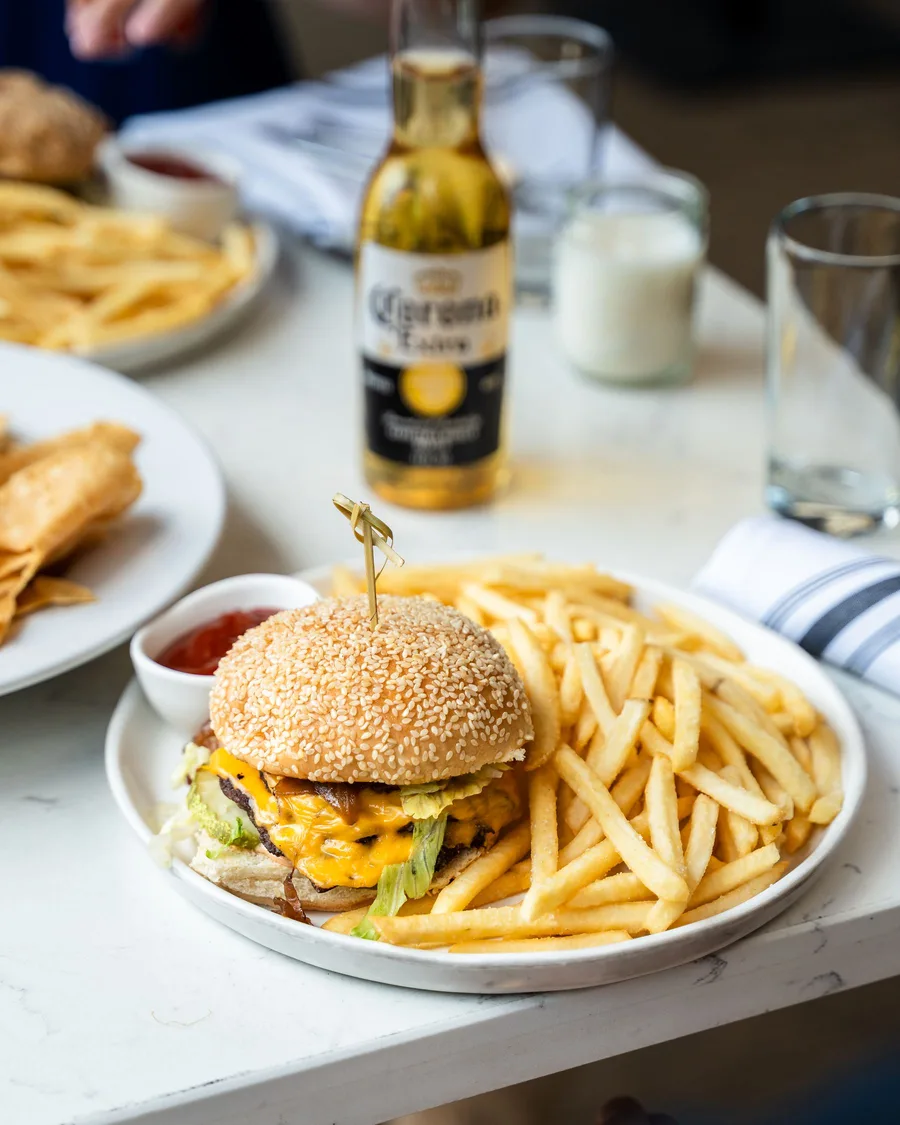 A cheeseburger and fries plated tableside, with sides shared around the table