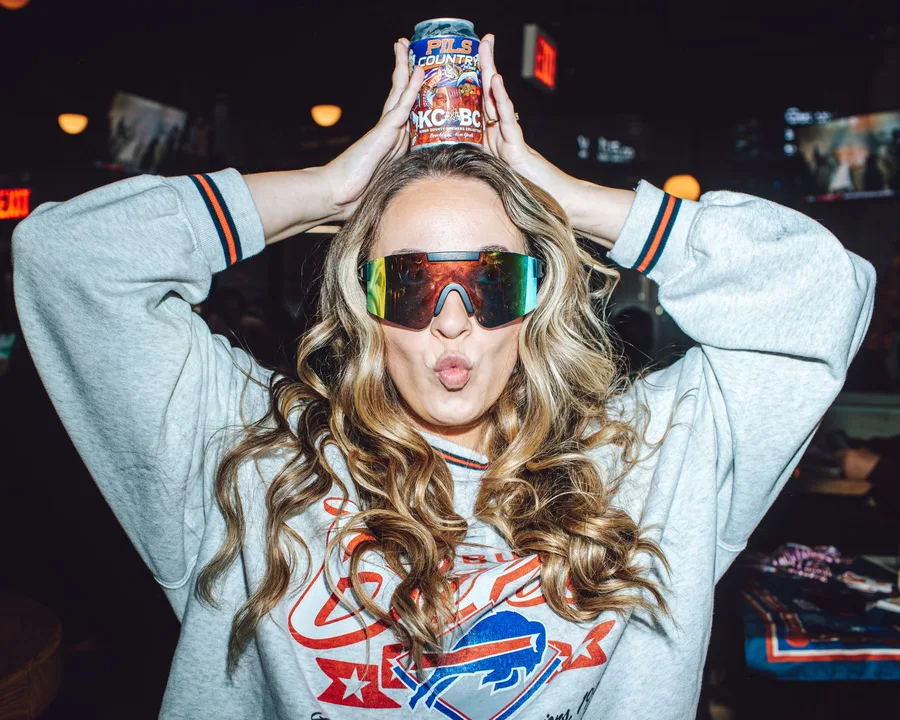 A guest celebrating with a beer can balanced on her head at the bar