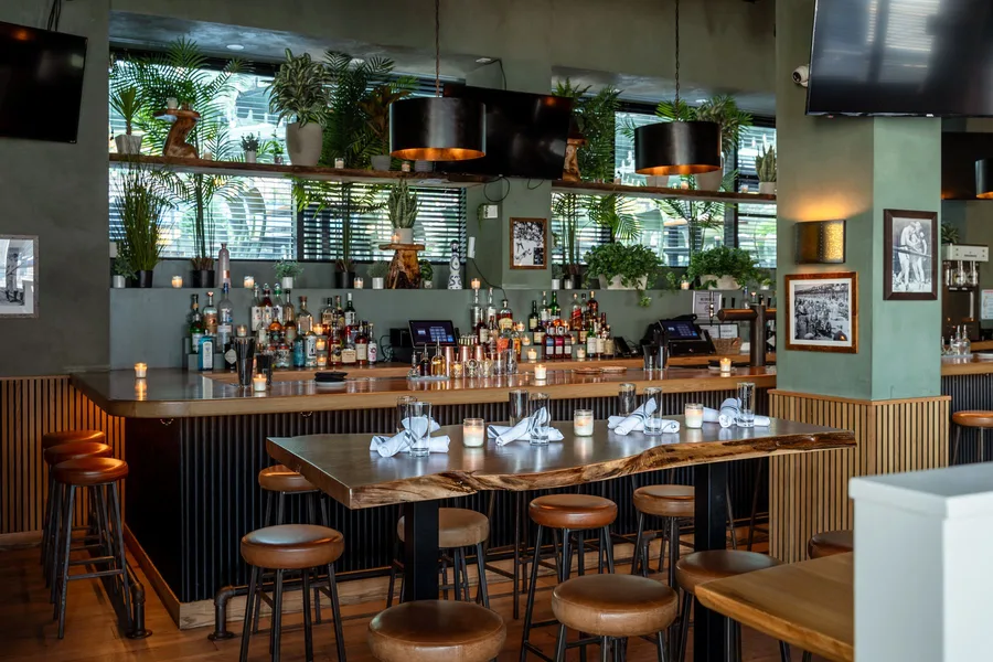A live-edge communal table at The Rutherford, set for service under hanging lamps
